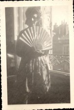 snapshot femme devant une fenêtre avec un éventail soleil rideaux rembarde 