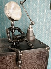 Lampe industrielle constituée de tuyau avec un vieux phare de voiture Ducelier