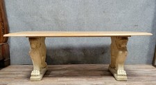 Table en pierre , piètement à décor de protomes de lions ailés, le plateau bois