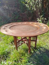 Grande table basse ancienne en cuivre rouge martelée sur pieds en bois sculpté