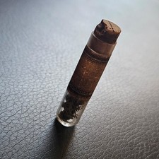 Tube en verre soufflé contenant des pièces d'horlogerie à définir