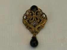 Broche ancienne en métal doré et pierres noires.