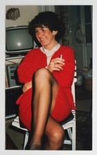 Femme chic jambes croisées tailleur rouge fume salon tv - Photo vintage 1980