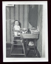 photo ancienne enfant dans sa chaise haute . scène de vie