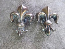 DEUX BOUTONNIERES en métal argenté, à décor de FLEURS DE LYS. Anciennes.