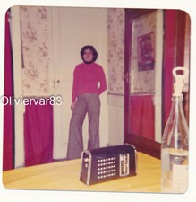 Vintage photo - woman in bell bottom pants, old radio set, clown poster