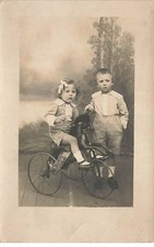 Deux enfants, la fillette assise sur un tricycle avec tête de cheval - vélo