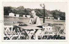 Vintage photo - shirtless man in swimsuit sitting at bar terrace on river side