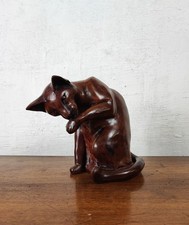 sublime sculpture de chat marron en train de se lécher la patte
