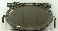 Miroir Art Déco ovale à patine argenté, surmonté de 2 dragons ou gargouilles.
