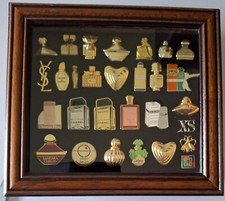 Très belle collection de 28 pin's parfumeurs livrée dans sa vitrine à pin's