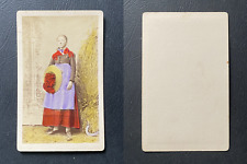 Jeune fille en costume régional posant devant une meule de foin, paille et fauci