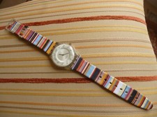   Swatch  fond crème , avec bracelet multicolore neuf , bon état , pile neuve