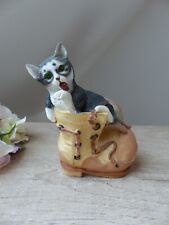 Figurine chat aux yeux verts curieux faisant sa toilette dans une chaussure