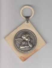 Médaille de berceau en galalithe avec angelot plaqué argent. signée E .DROPSY.