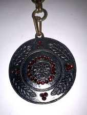Porte clés métal / Pendentif : disque noir ciselé de feuilles et orné de pierres