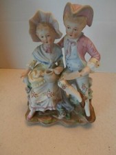 ANTIQUE FIGURAL GROUP A COURTING COUPLE SEATED ON TREE TRUNKS AT A GARDEN GERMA