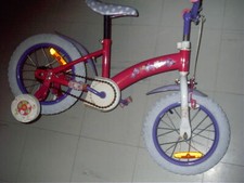 UN VELO ROUGE POUR ENFANT AVEC SES DEUX ROUES ARRIERES DE SOUTIENT