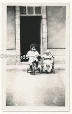 Vintage photo - little girl and baby on tricycle by old door