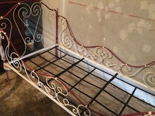 Lit ancien en fer à volutes convertible en banquette
