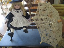 Jolie poupée en porcelaine vendu sans le banc en fer forgé ni le parasol 