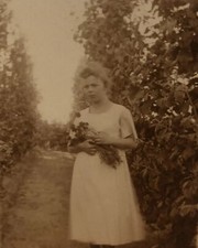 c1915 Photo of Beautiful Young Woman, White Dress Holding Flowers in Garden RPPC