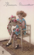 CP ROSE PETITE FILLE FRISEE ASSISE AVEC FER A CHEVAL FLEURS