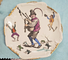 ANCIENNE ASSIETTE HUMORISTIQUE EN PORCELAINE - JOUEUR DE CORNEMUSE