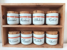 8 pots à épices en porcelaine d'Auteuil dans son petit meuble en bois.
