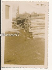 Vintage photo 1947 sepia - girl on bicycle by wood trunk stacks