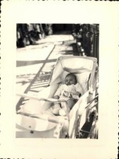 snapshot enfant dans landau poussette avec jouet marin ou cuisinier vers 1957
