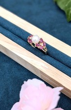 Bague or centrée d'une perle de culture blanche dans une pavage de Rubis navett