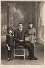 Carte-Photo Père assis, ses 2 filles debout de chaque côté.