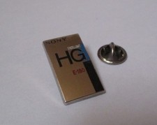 pin's Sony - cassette VHS E-180 excellent HG (zamac argenté signé Tosca) h:2,6cm