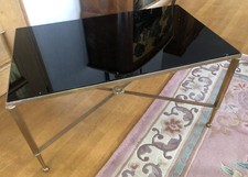 Table basse en métal doré, pieds reliés par entretoise dans le goût de BAGUES